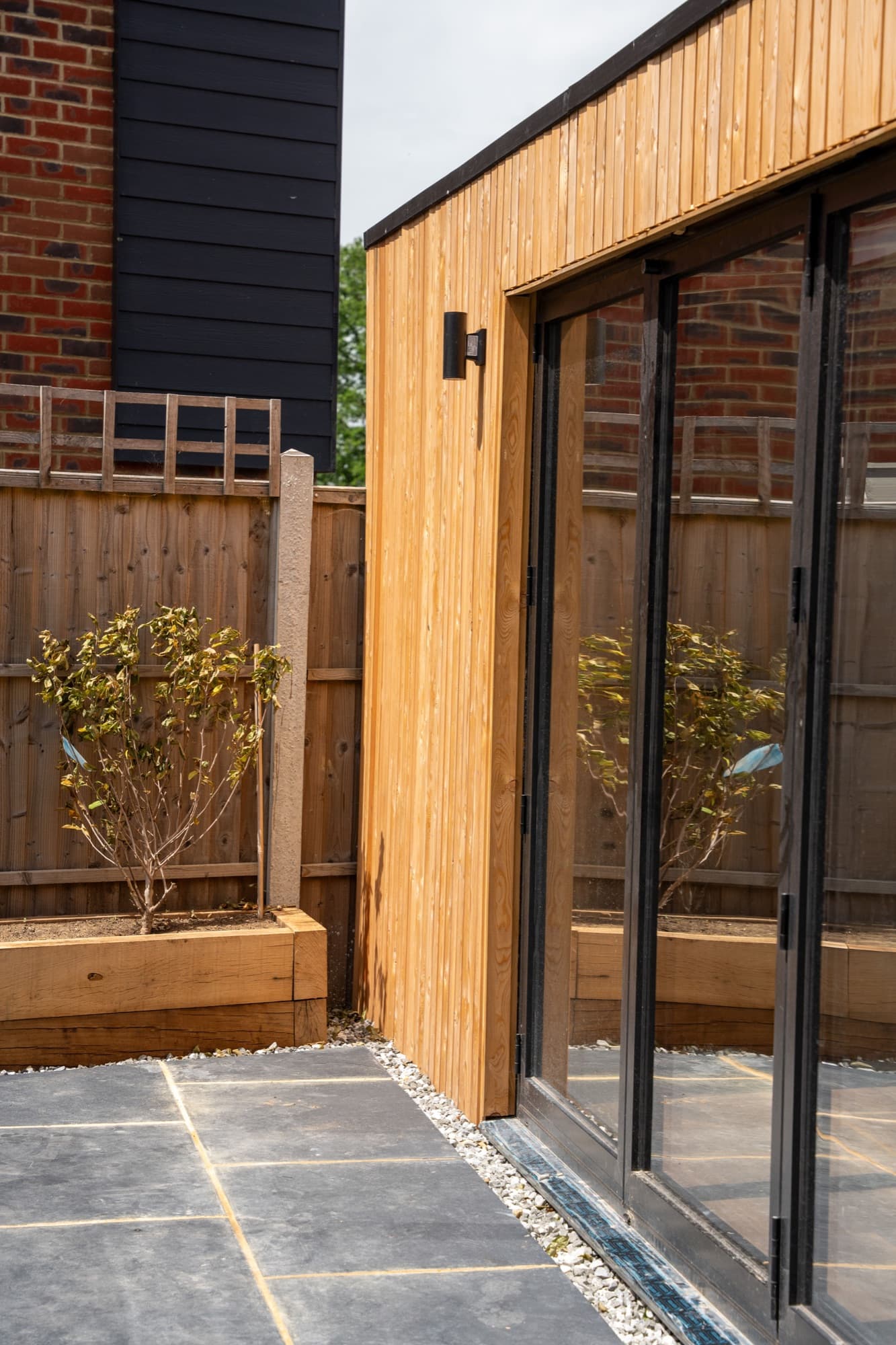 Corner detail of a garden room where slate paving meets timber cladding