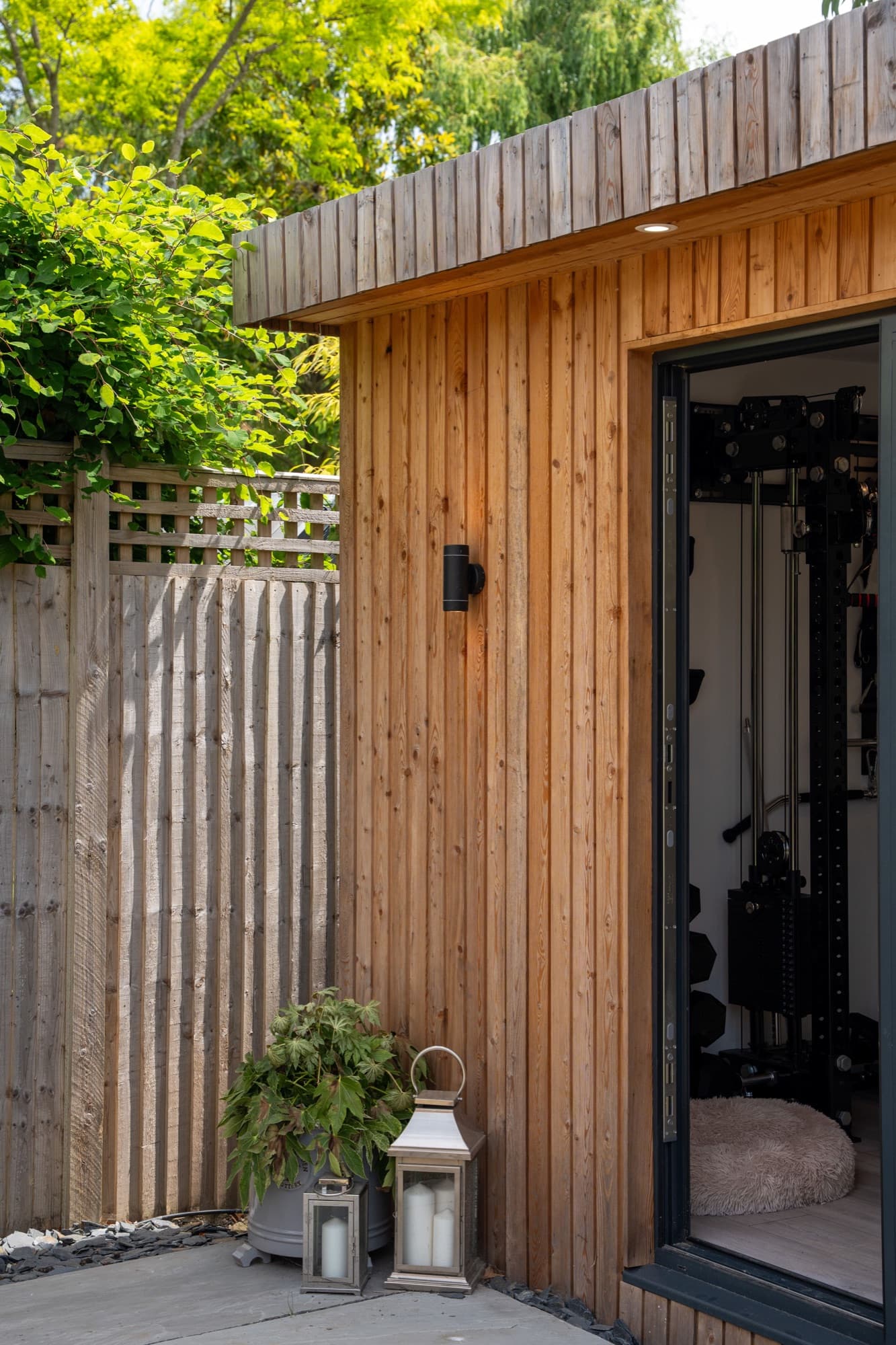 Timber clad garden room with full height glazed doors open onto a lawn